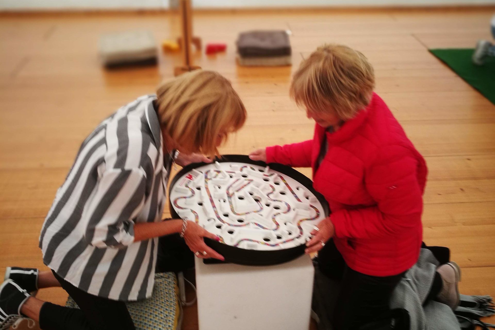 Deux femmes senior s'amusant avec le labyrinthe à bille géant petit modèle.