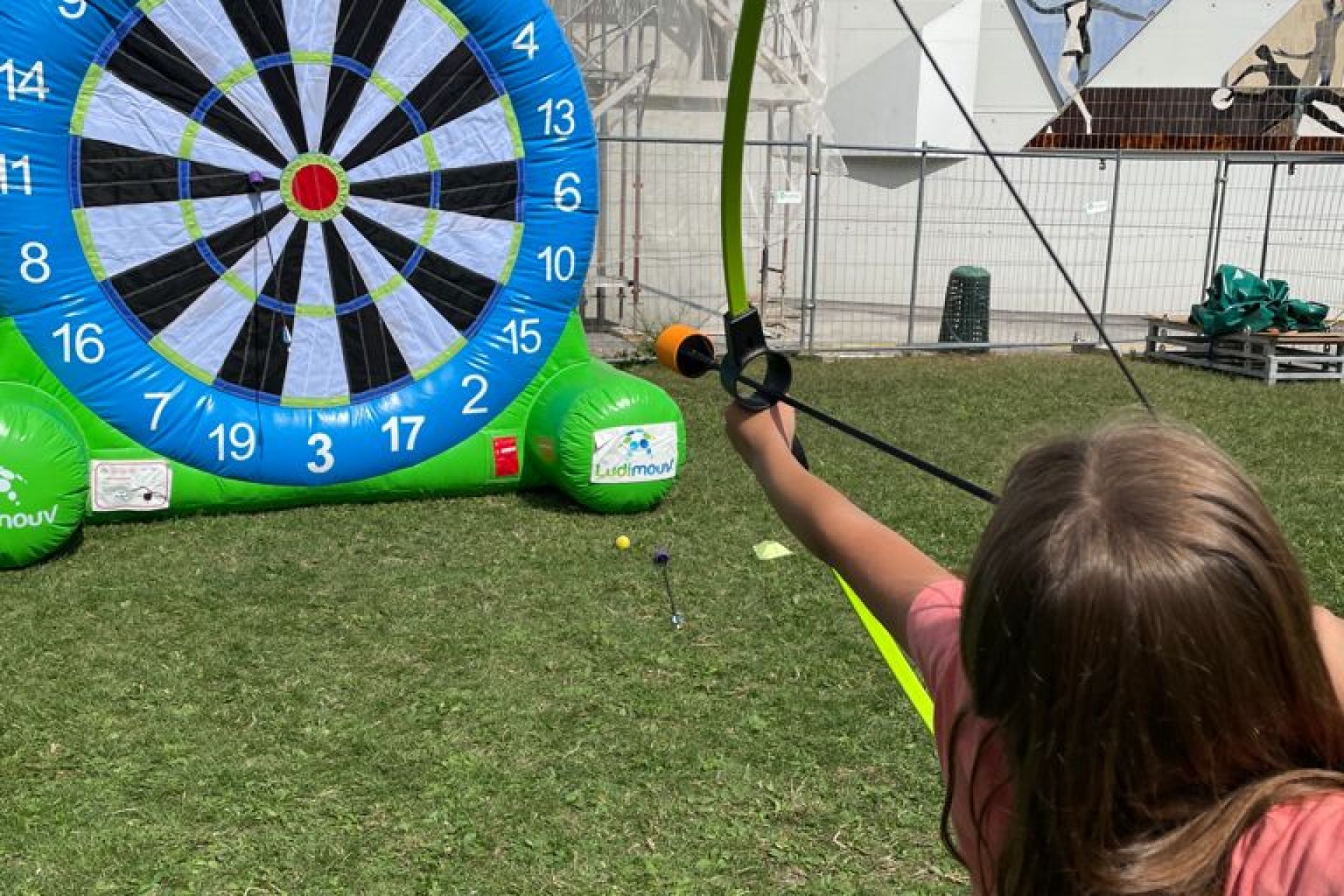 Petite fille pratiquant le tir à l'arc sur une cible géante gonflable scratch, avec flèche à embout mousse