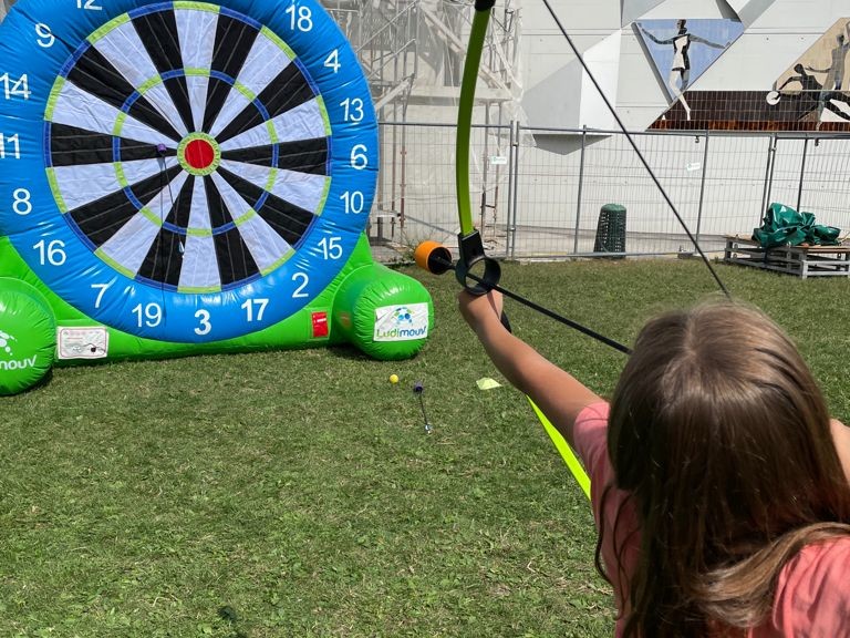 Petite fille pratiquant le tir à l'arc sur une cible géante gonflable scratch, avec flèche à embout mousse