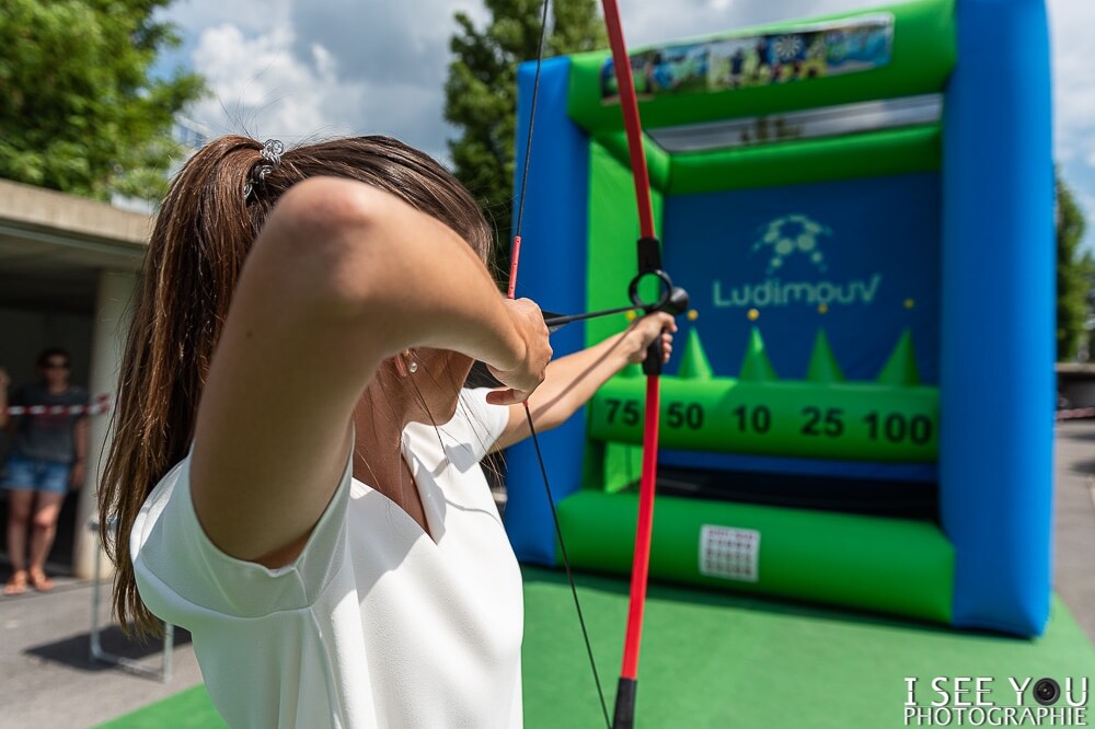 Jeune femme avec arc et flèche prête à tirer sur une cible du stand de tir à l'arc gonflable