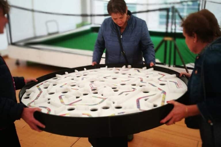 Labyrinthe à bille géant avec 3 joueuses très concentrées pour éviter les pièges !