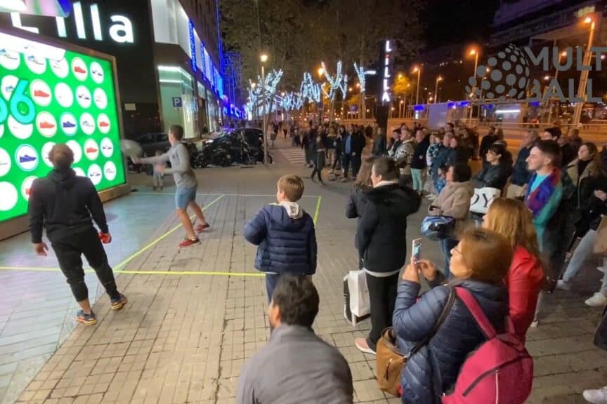 Les badauds se pressent pour regarder cette partie de jeu vidéo sportive en extérieur.